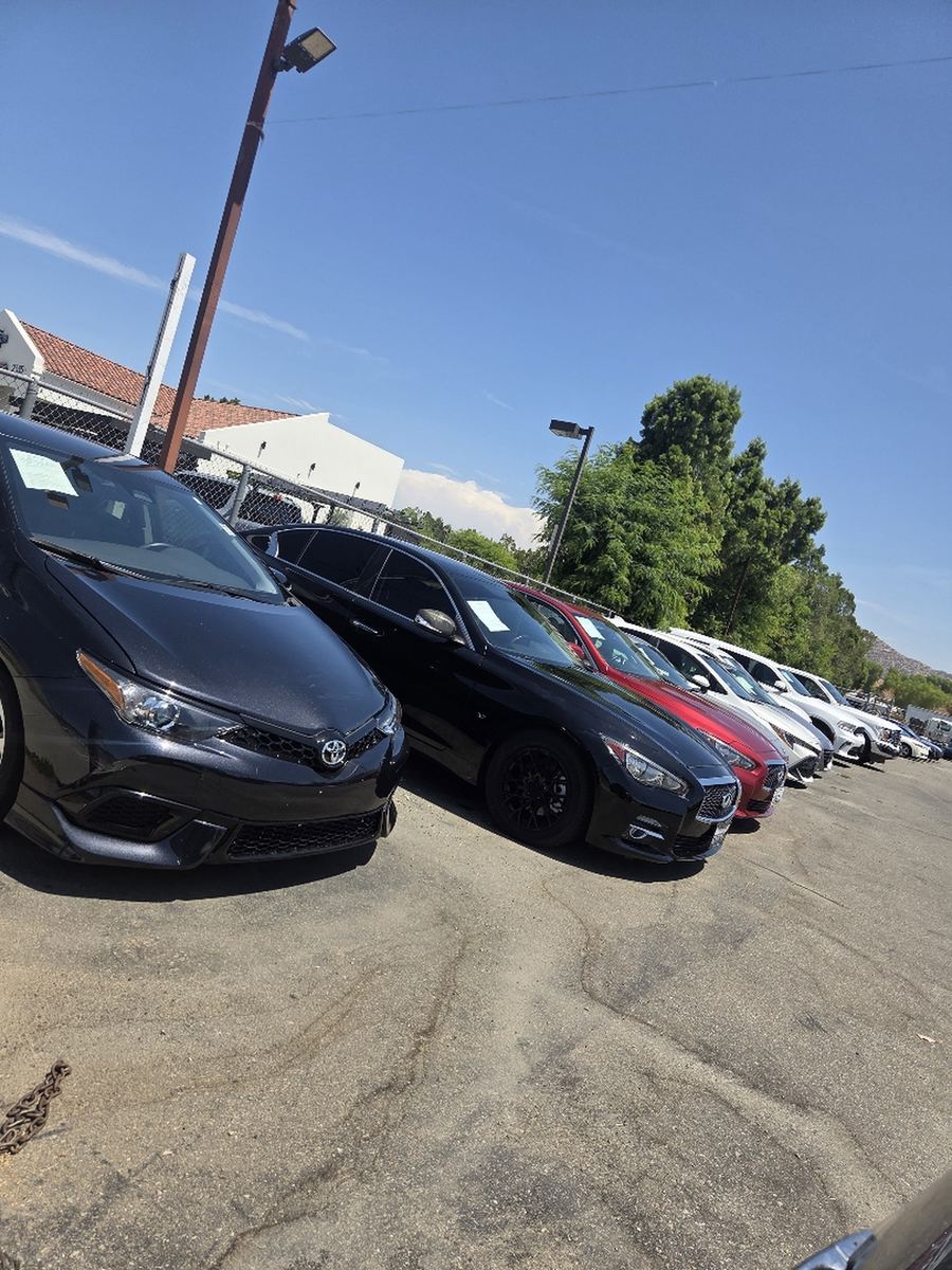 A row of used cars parked nose-to-tail on a sales lot