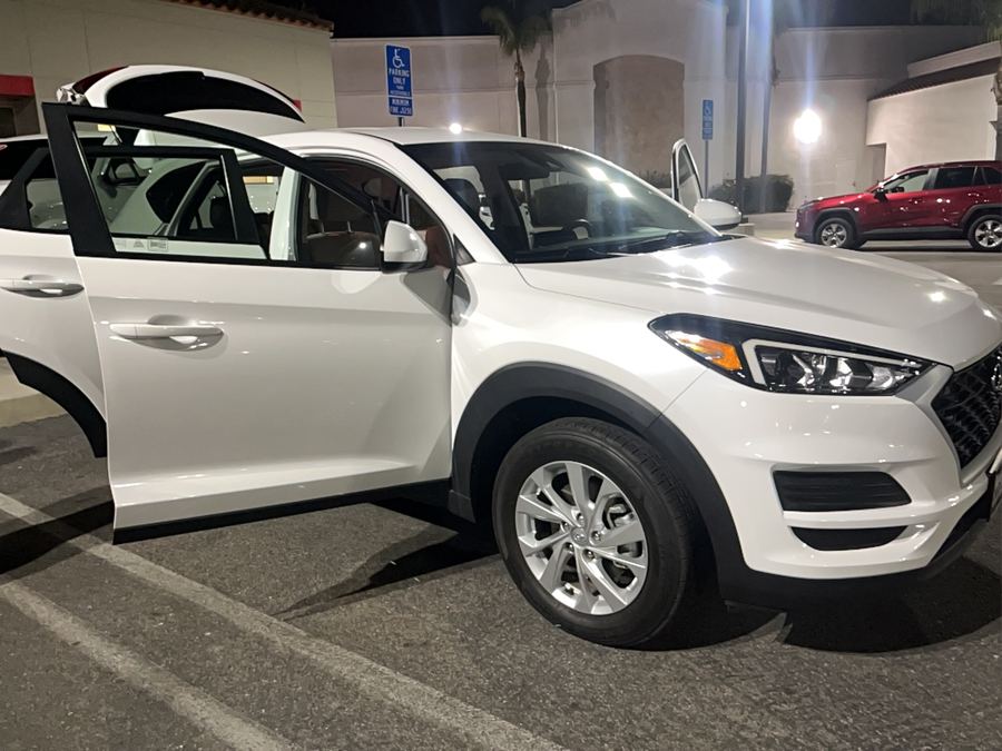 White Hyundai Tucson on a lot at night with its doors and hatch open