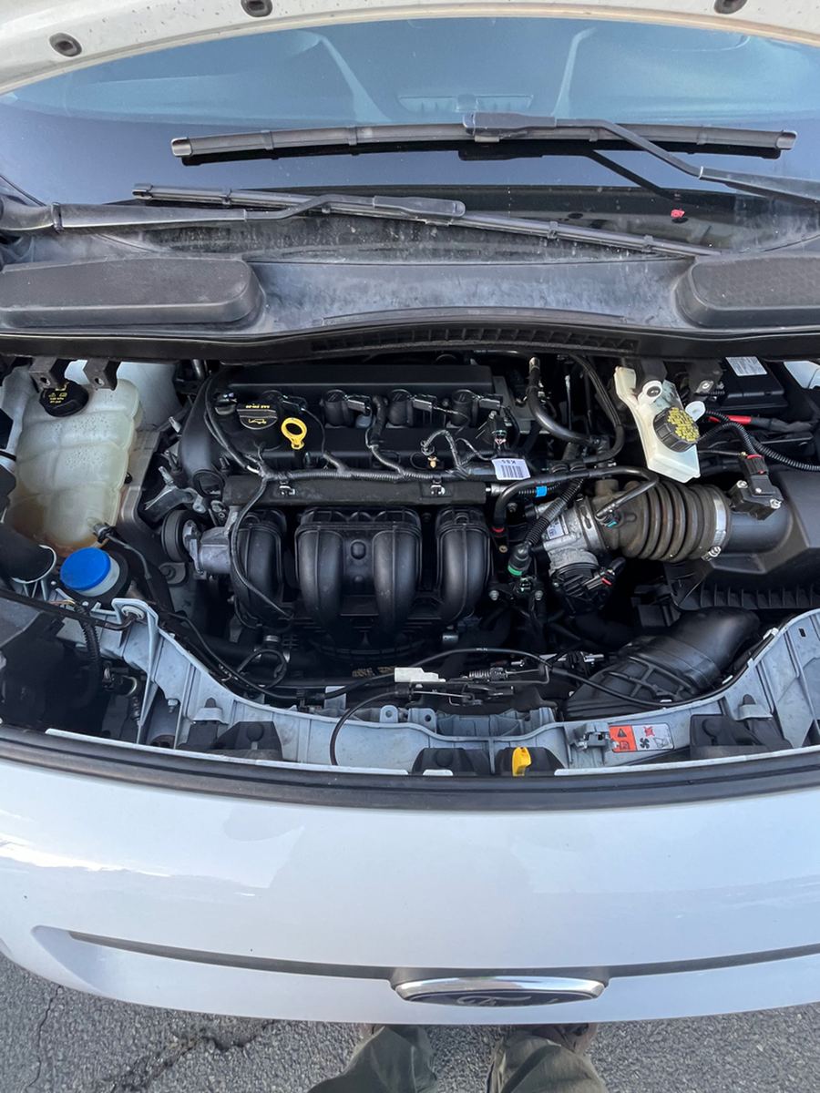 Small van engine bay with the hood raised on a used car lot