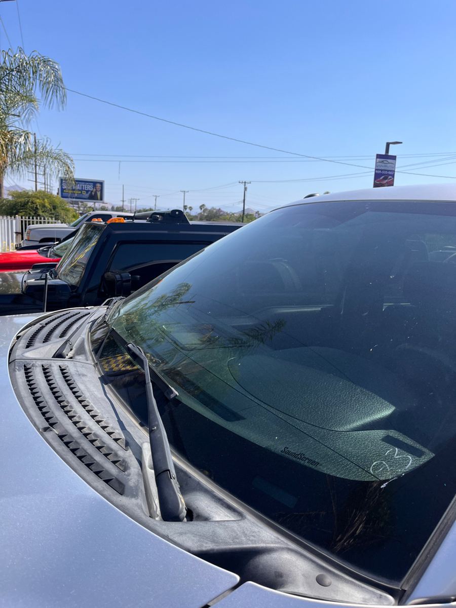 Windshield glass and cowl of a silver pickup seen from outside