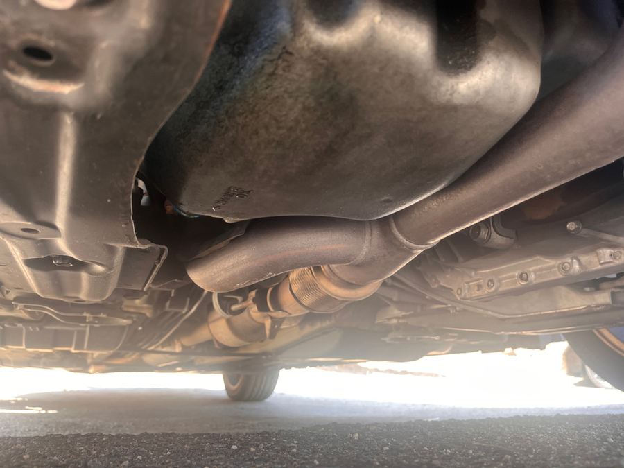 Exhaust pipe and underbody panels seen from beneath a car