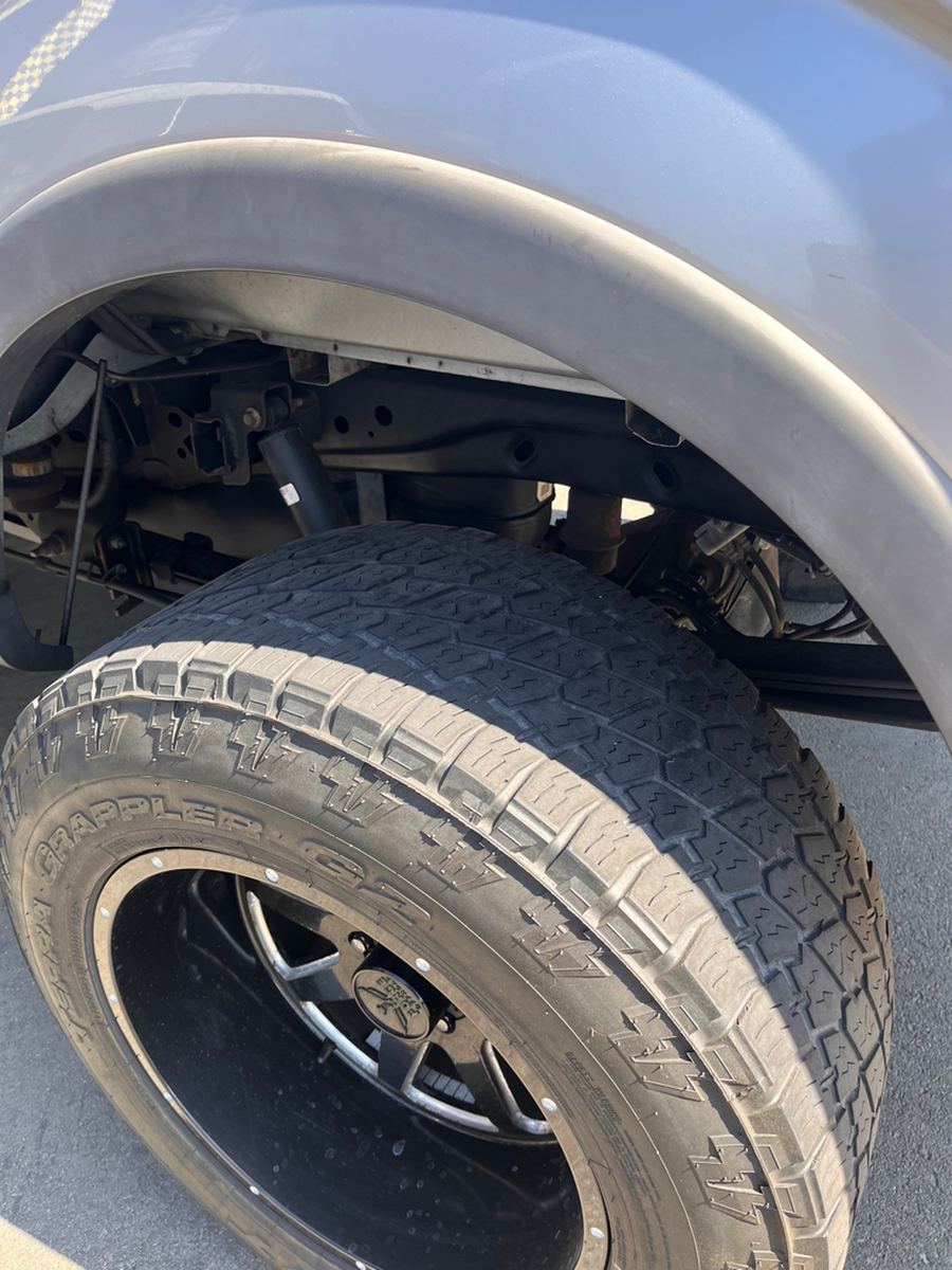 Close-up inside a front wheel arch showing the coil spring, shock absorber and inner fender