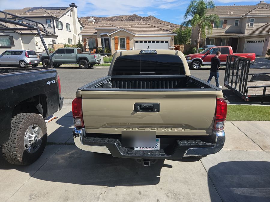 Toyota Tacoma pickup parked in a suburban driveway, number plate blurred