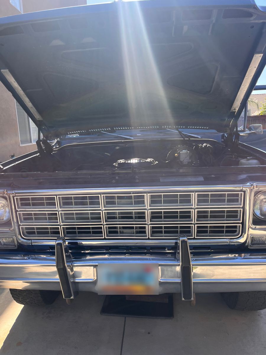 Front grille and chrome bumper of a 1970s Ford pickup with the hood raised