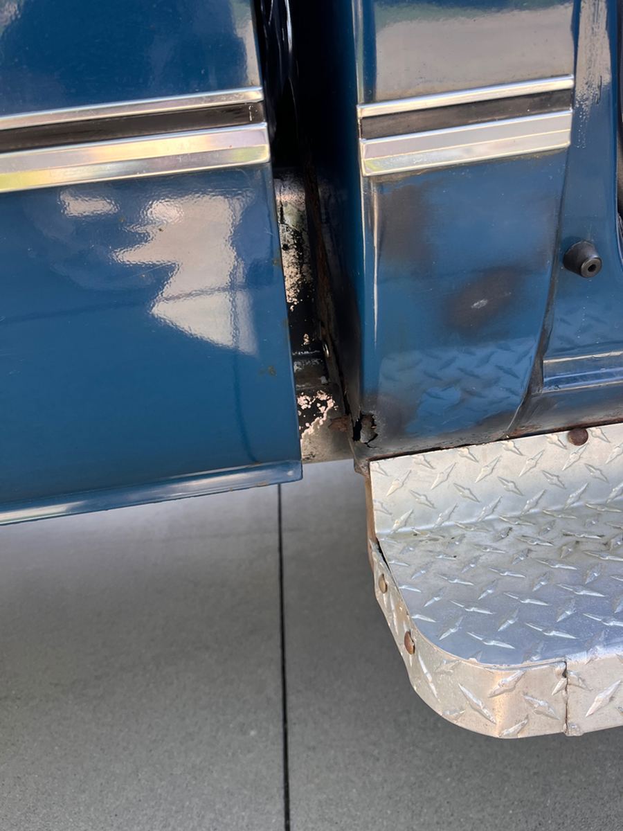Rust at the bottom of a blue pickup door and cab corner above a diamond plate step