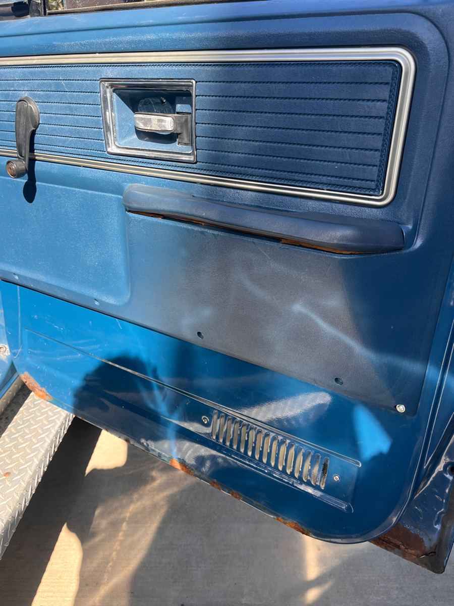Original blue door panel with chrome trim and a paddle handle inside a 1970s pickup
