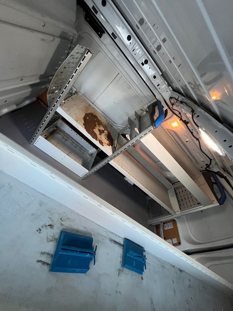Metal shelving and a parts drawer racked along the inside of a cargo van