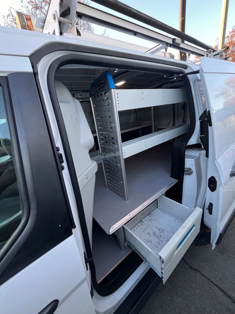 Shelving and a pull-out drawer seen through the sliding side door of a cargo van