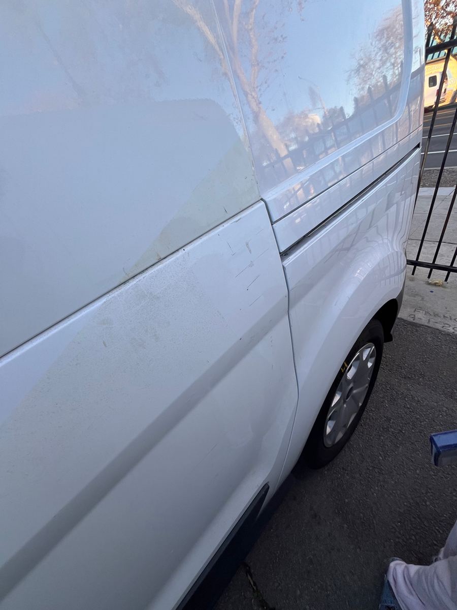 Scuffs and scrapes along the white side panel of a cargo van