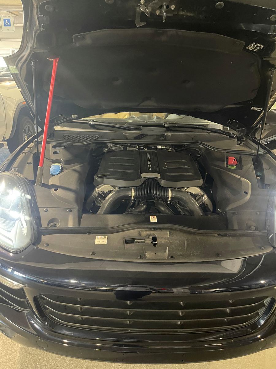 Porsche Cayenne with the hood propped open in a parking garage