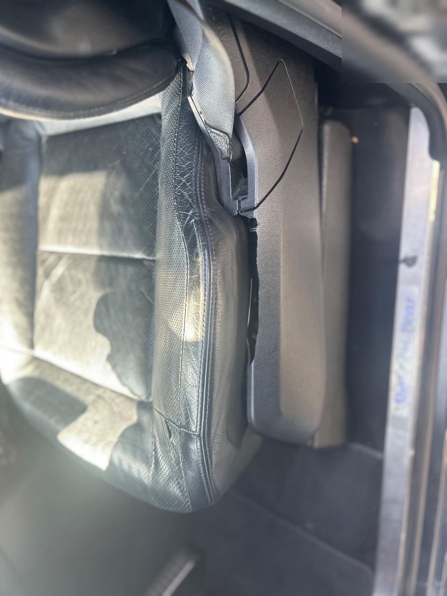 Black leather driver seat with a creased, worn side bolster