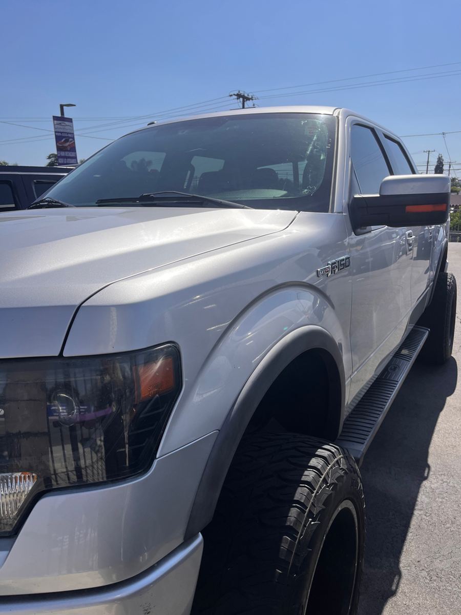 Front corner of a silver Ford F-150 on a dealer lot