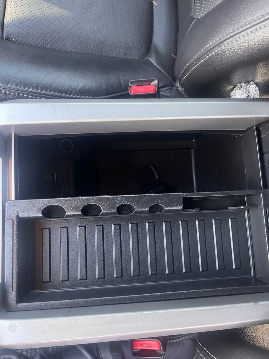 Center console storage bin open between the front seats of a pickup