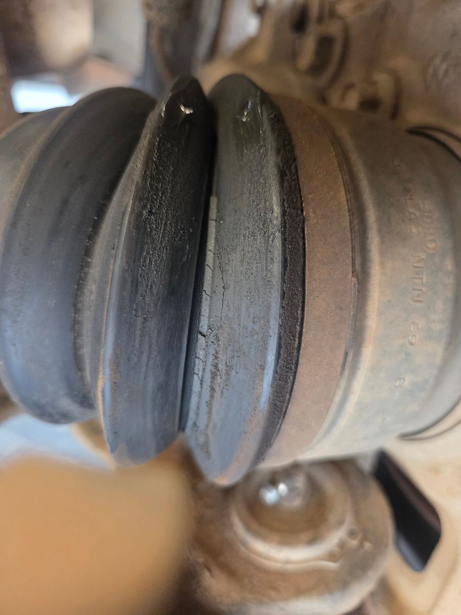 Close view of a rubber axle boot cracked through its folds