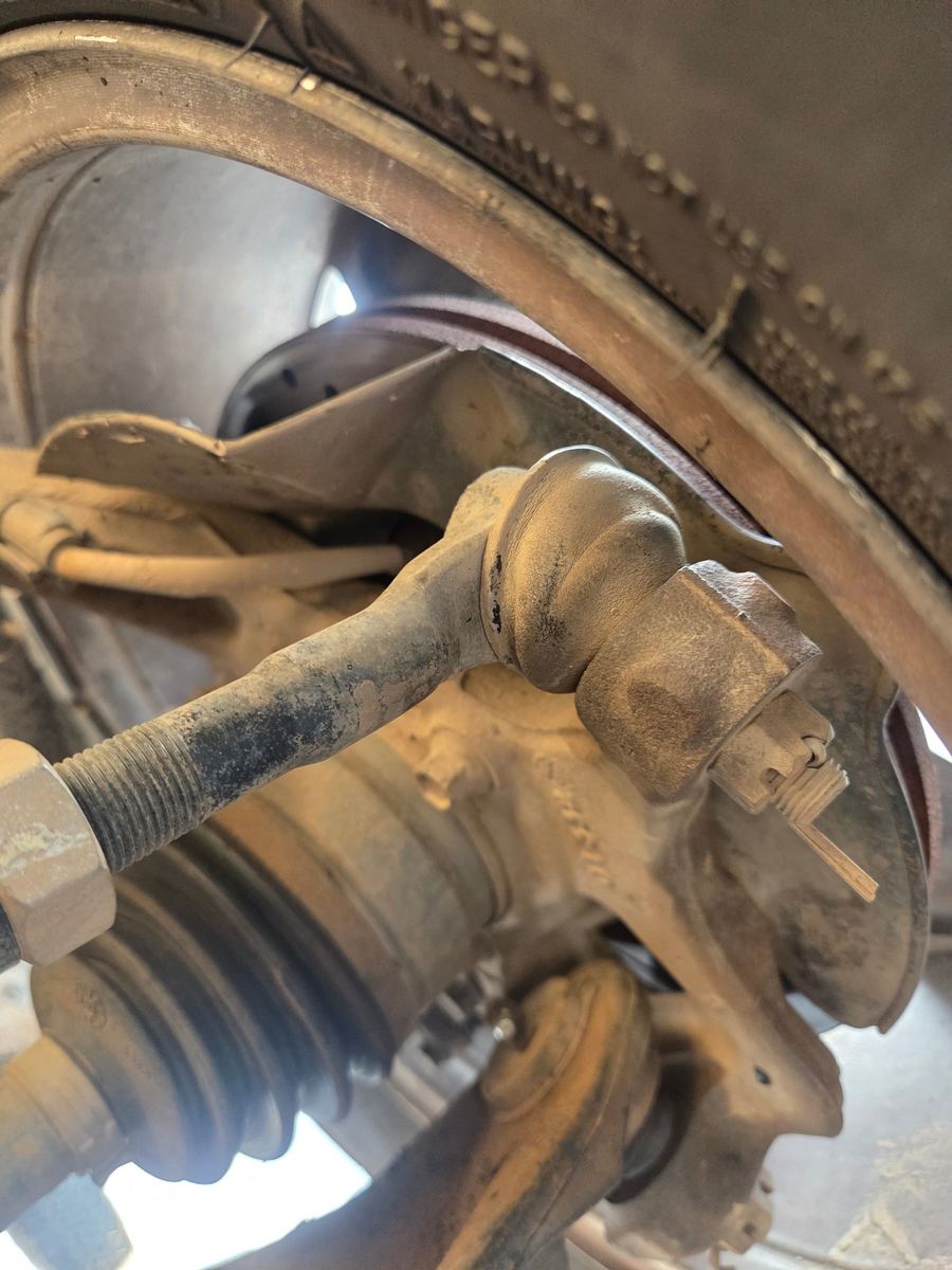 Tie rod, steering knuckle and axle boot behind a pickup's front wheel