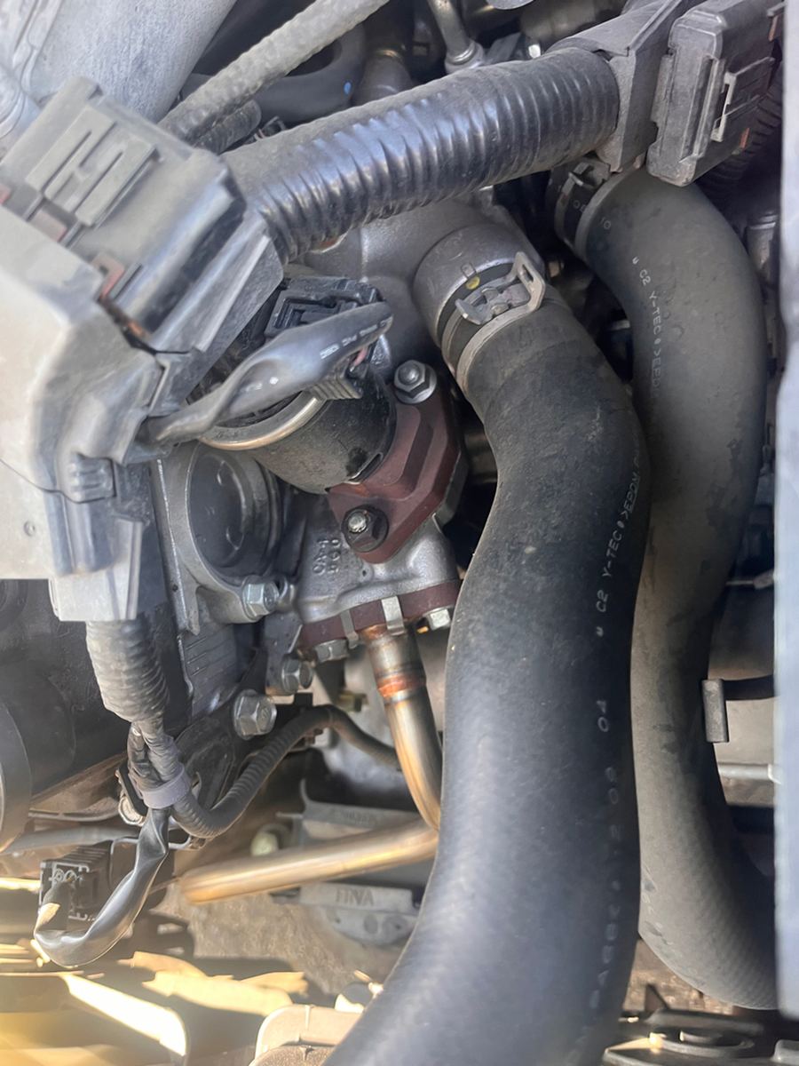 Engine bay detail showing coolant hoses, wiring connectors and the thermostat housing