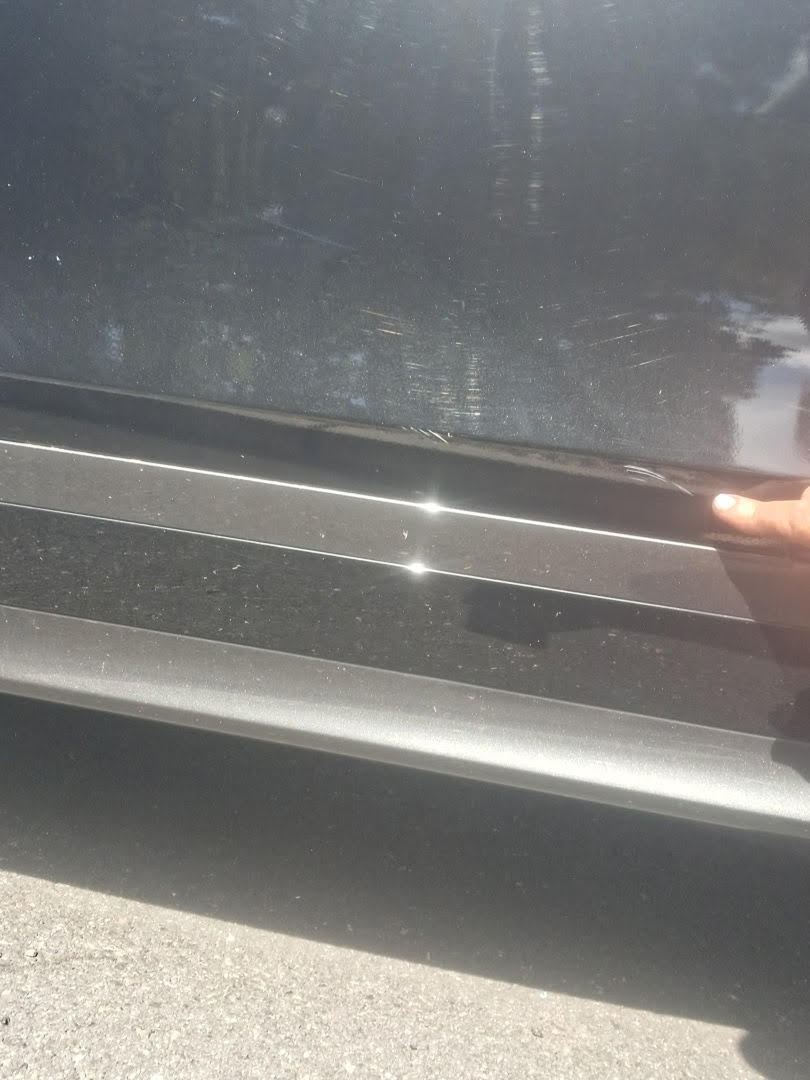 Fine scratches in black door paint above a silver trim strip