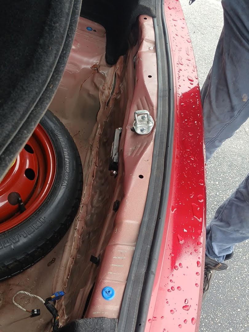 Open trunk of a red Hyundai, showing the spare tire well and trunk edge