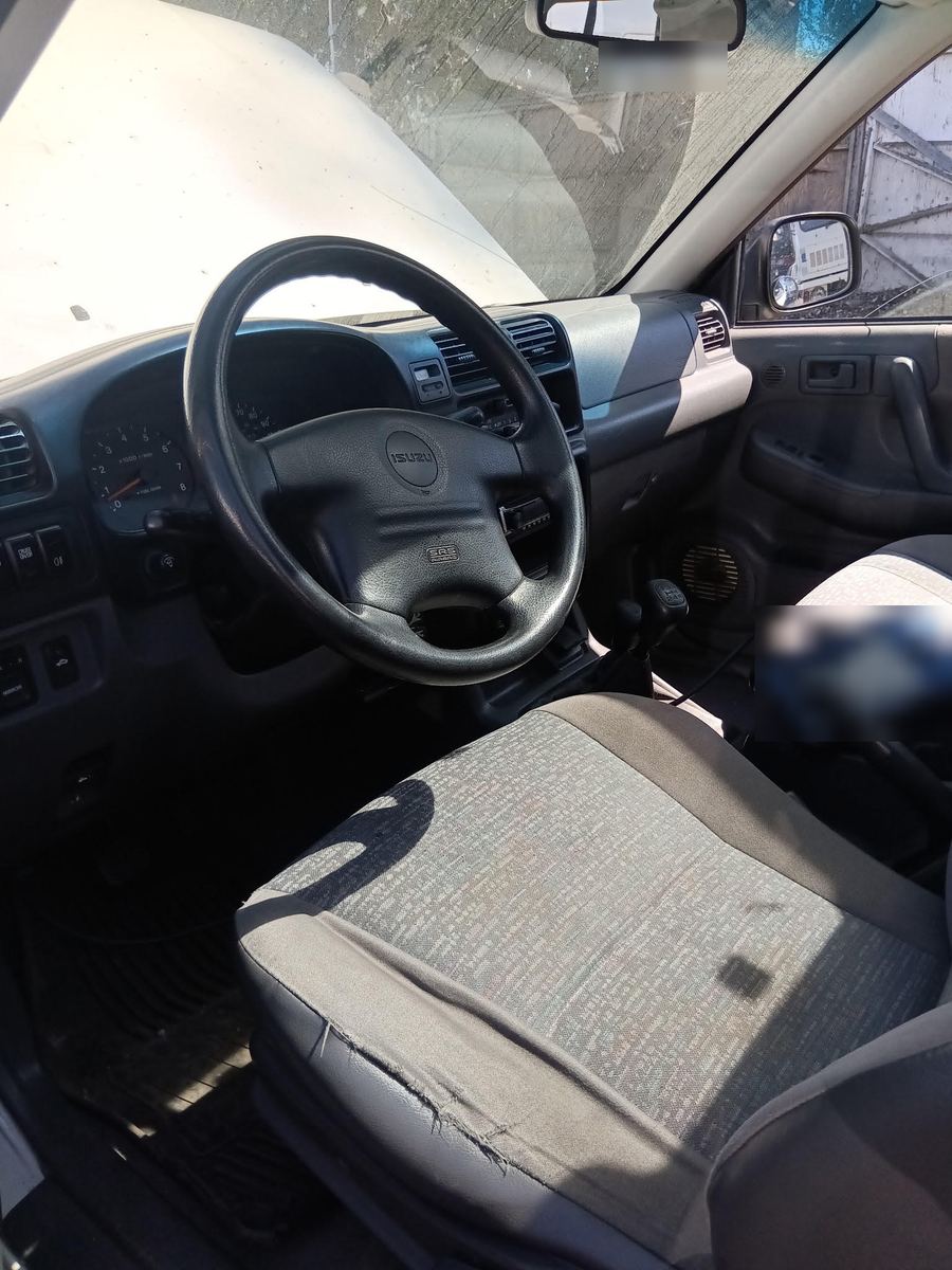 Isuzu dashboard and steering wheel with a scan tool resting on the seat