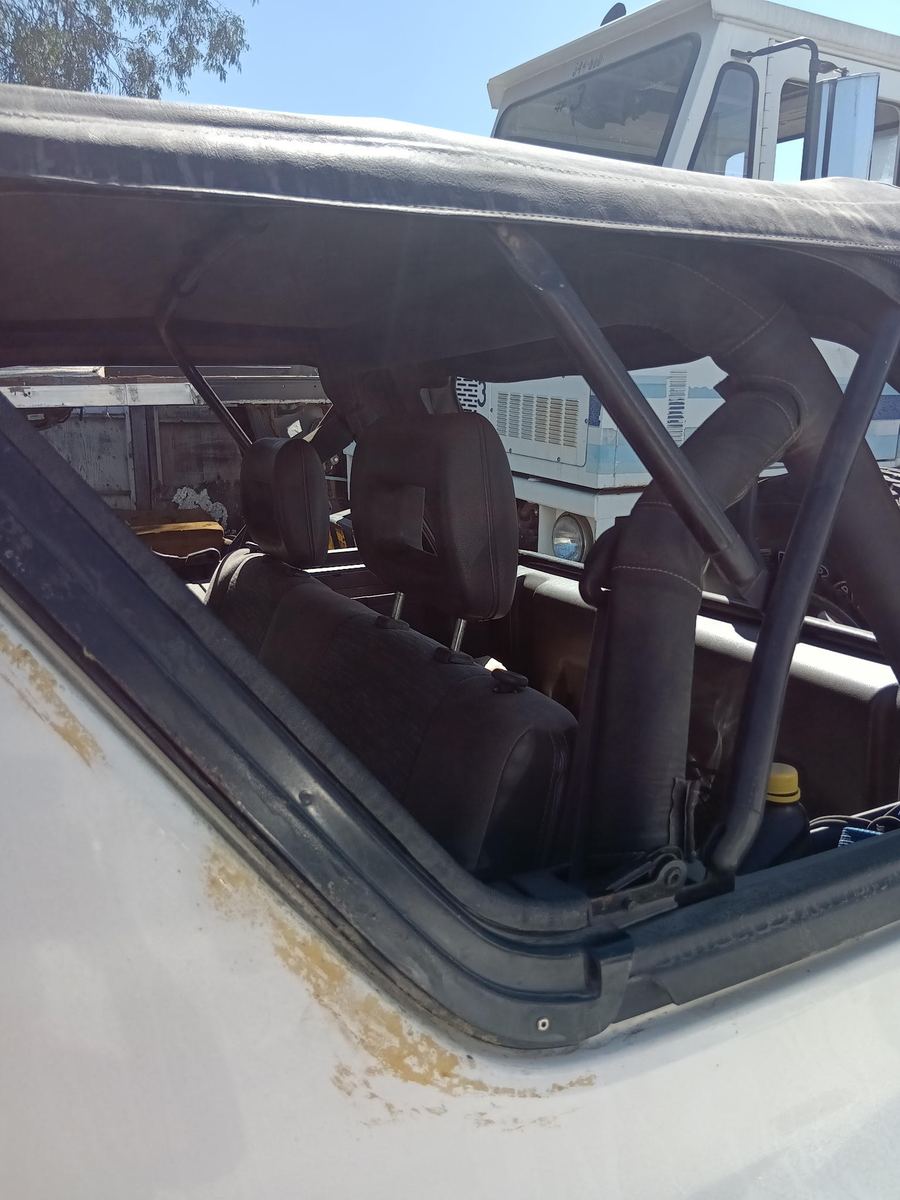 White body panel with orange rust spots below a soft top window