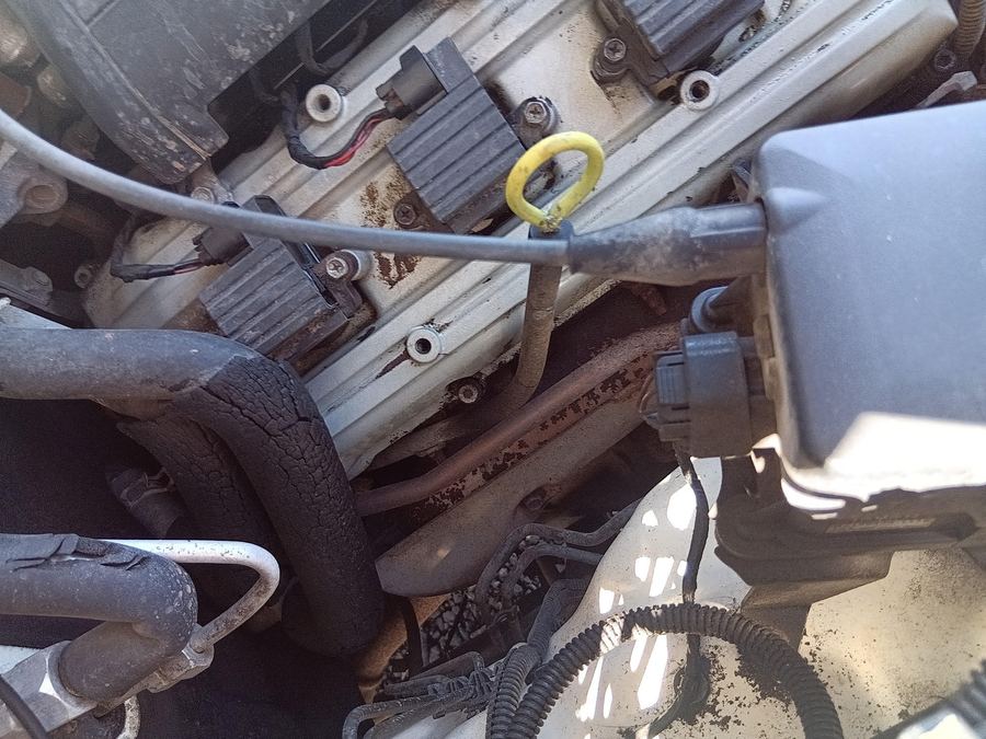 Top of a V6 engine with coil packs, the dipstick and oil stained metal