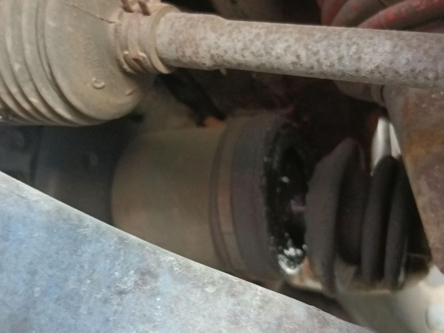 CV axle boot and clamp with dark grease around it, seen from below