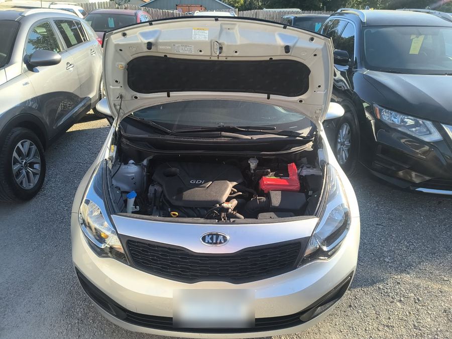 Kia Rio with the hood propped open on a dealer lot