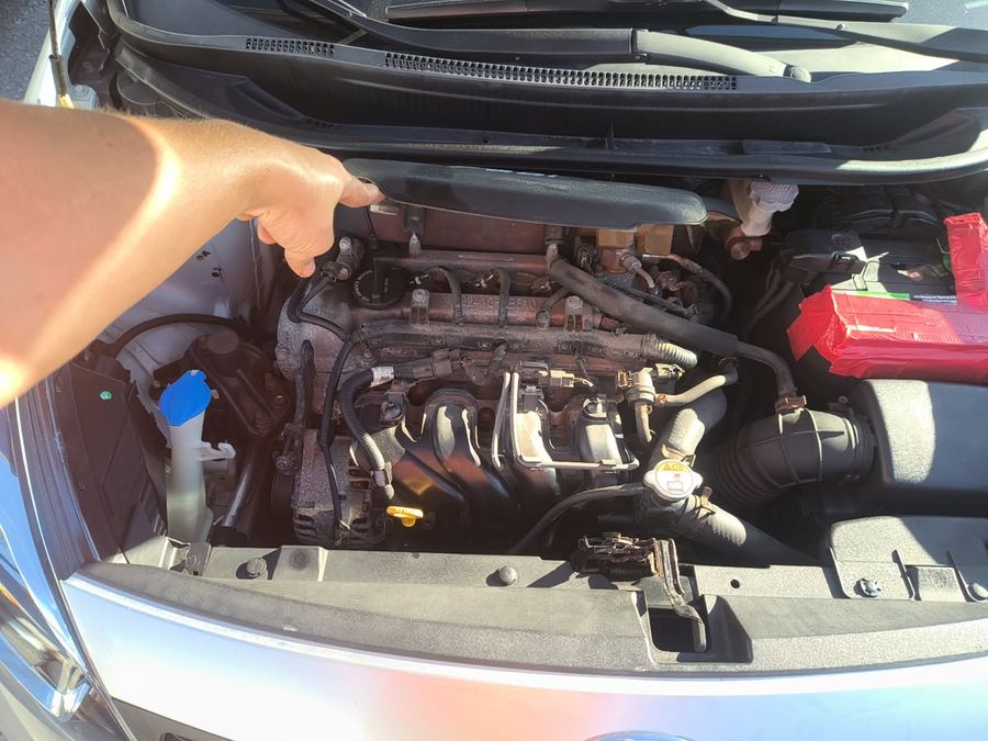 Technician pointing into the engine bay of a Kia Rio