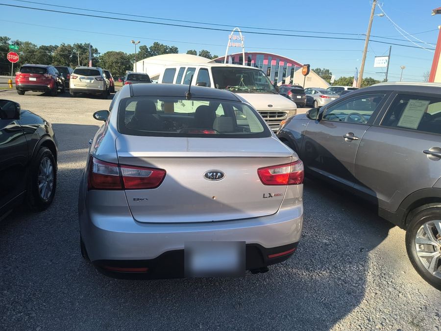 Rear of a silver Kia Rio LX sedan on a dealer lot