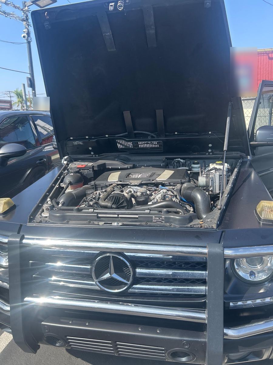 Black Mercedes-Benz G-Class with its hood open on a sunny dealer lot