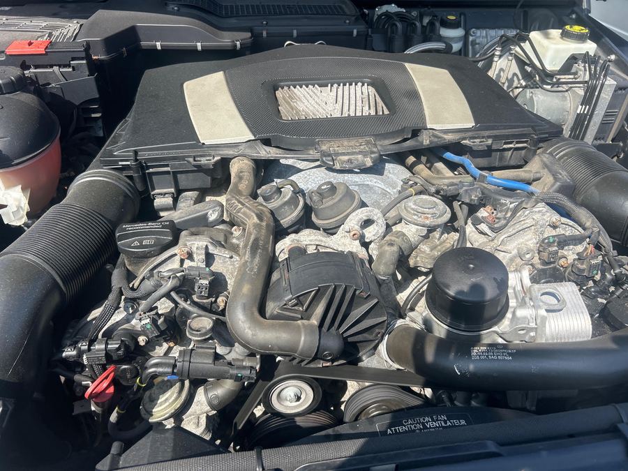 Mercedes engine under its cover, with hoses and the oil filler cap in view