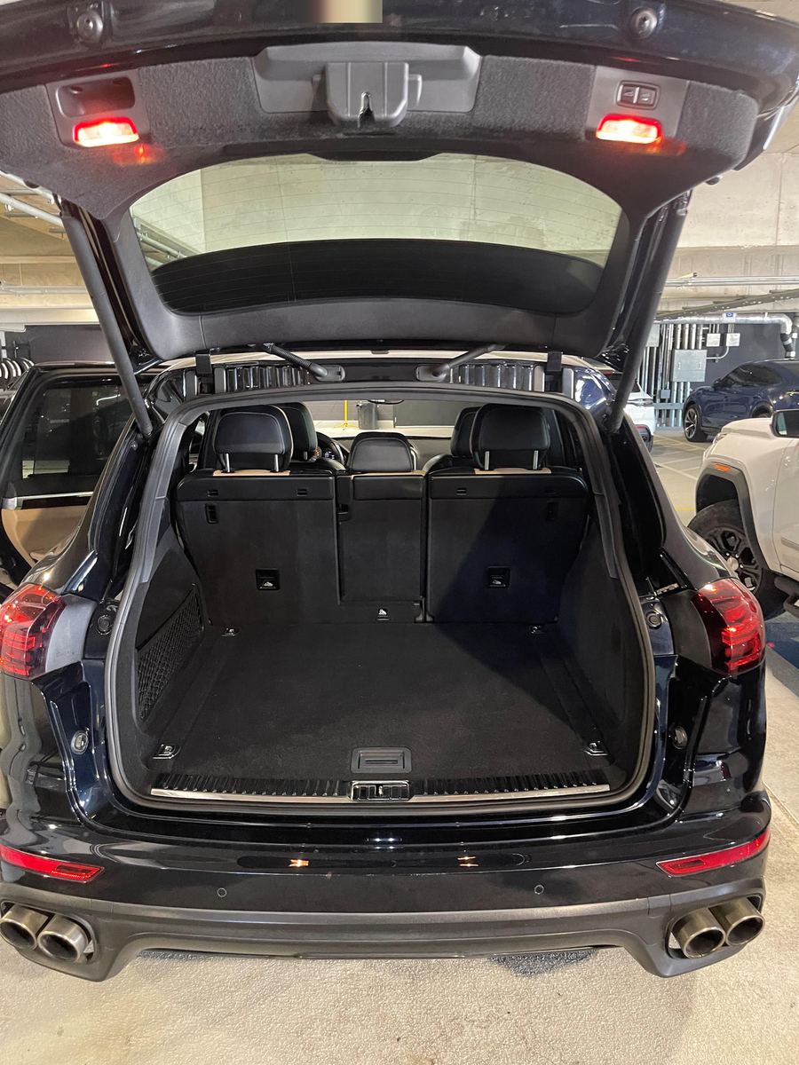 Porsche Cayenne with the rear hatch open, showing the cargo floor and rear seats