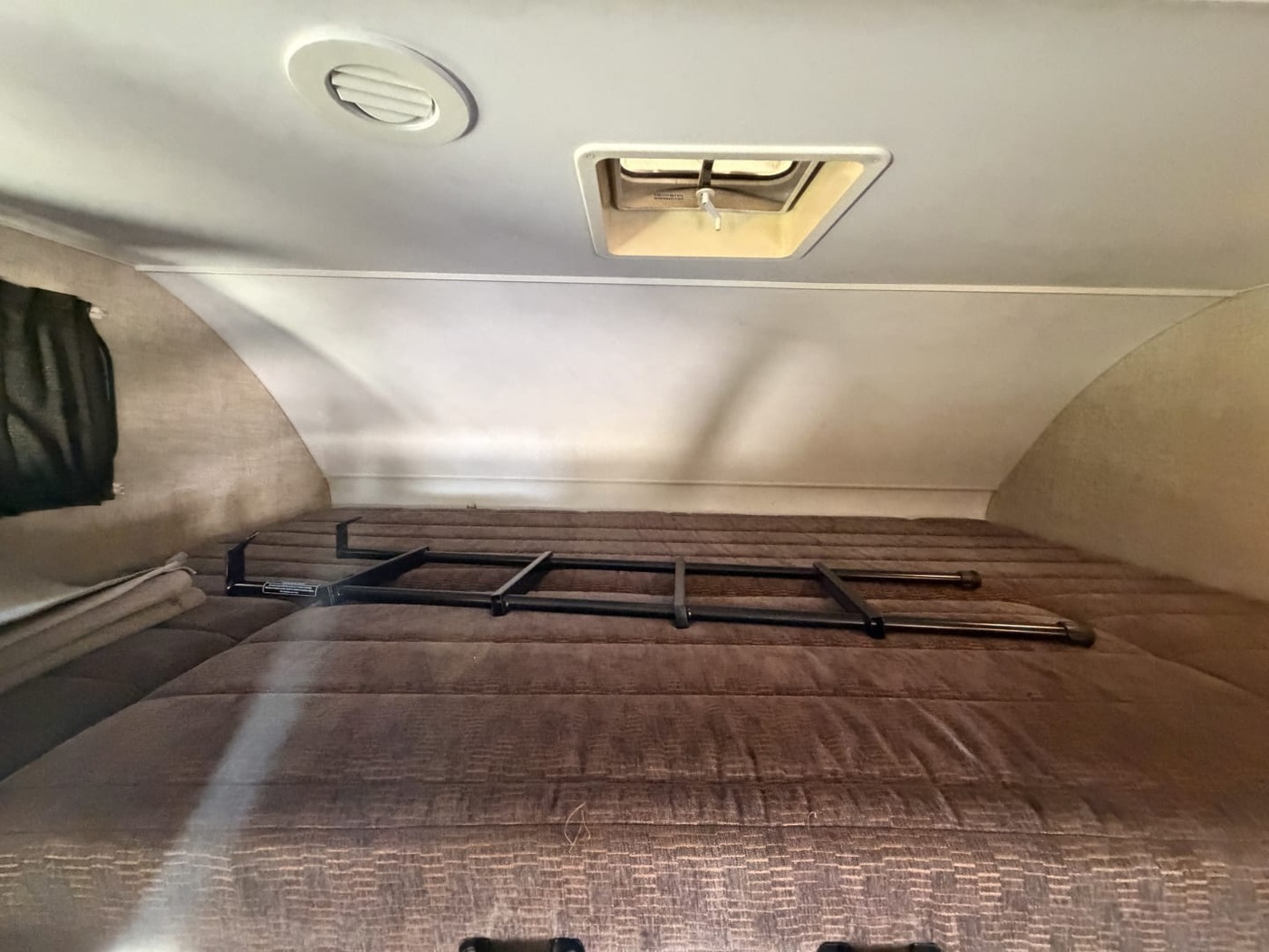Cab-over bed in a Class C motorhome with a ladder resting on the mattress
