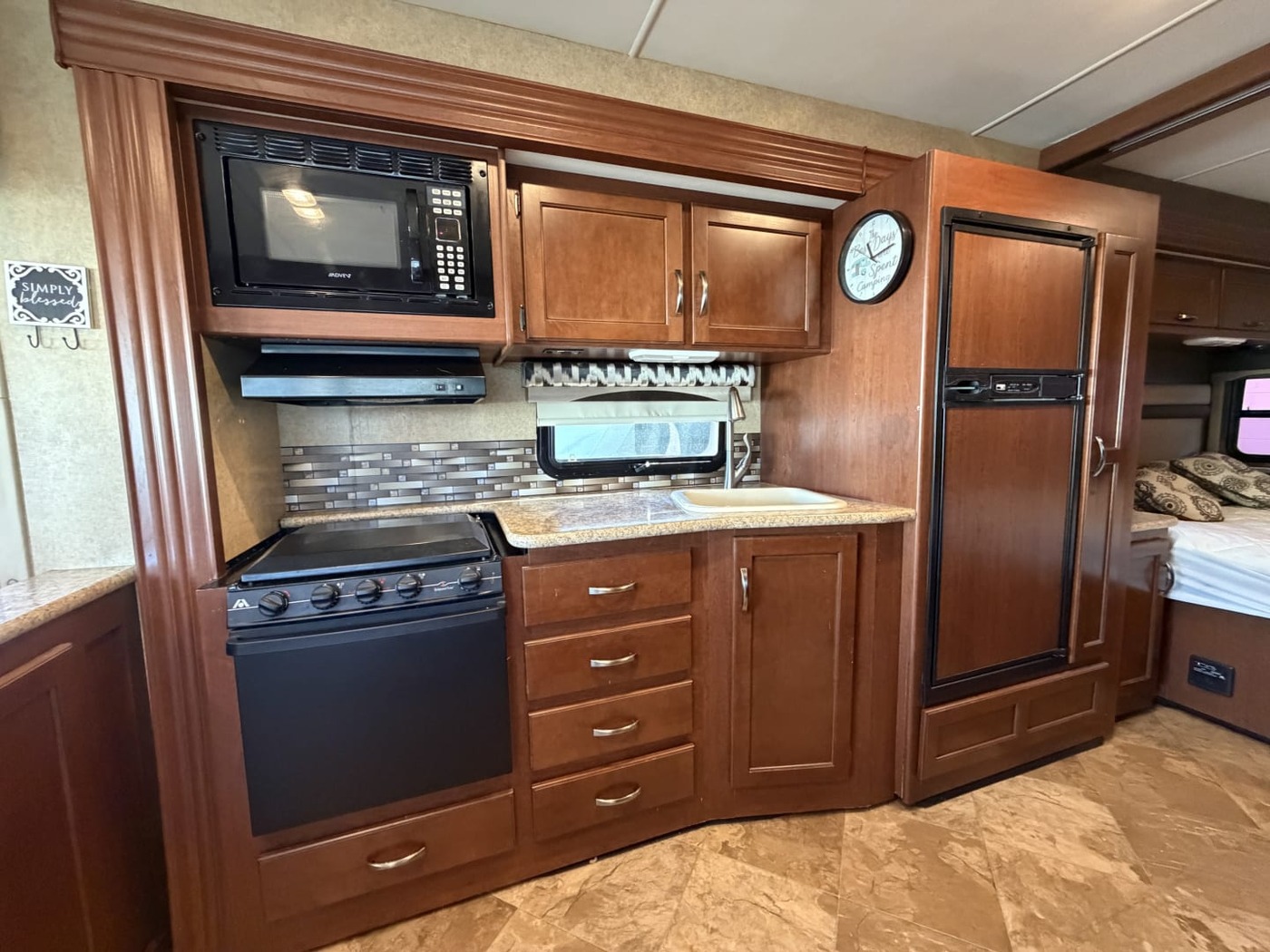 Motorhome kitchen with a microwave, gas range, wood cabinets and a two-door refrigerator
