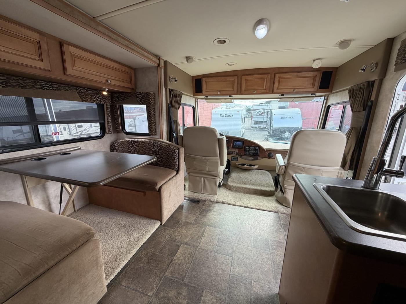 Inside a Class A motorhome looking forward past the dinette to the cab and windshield