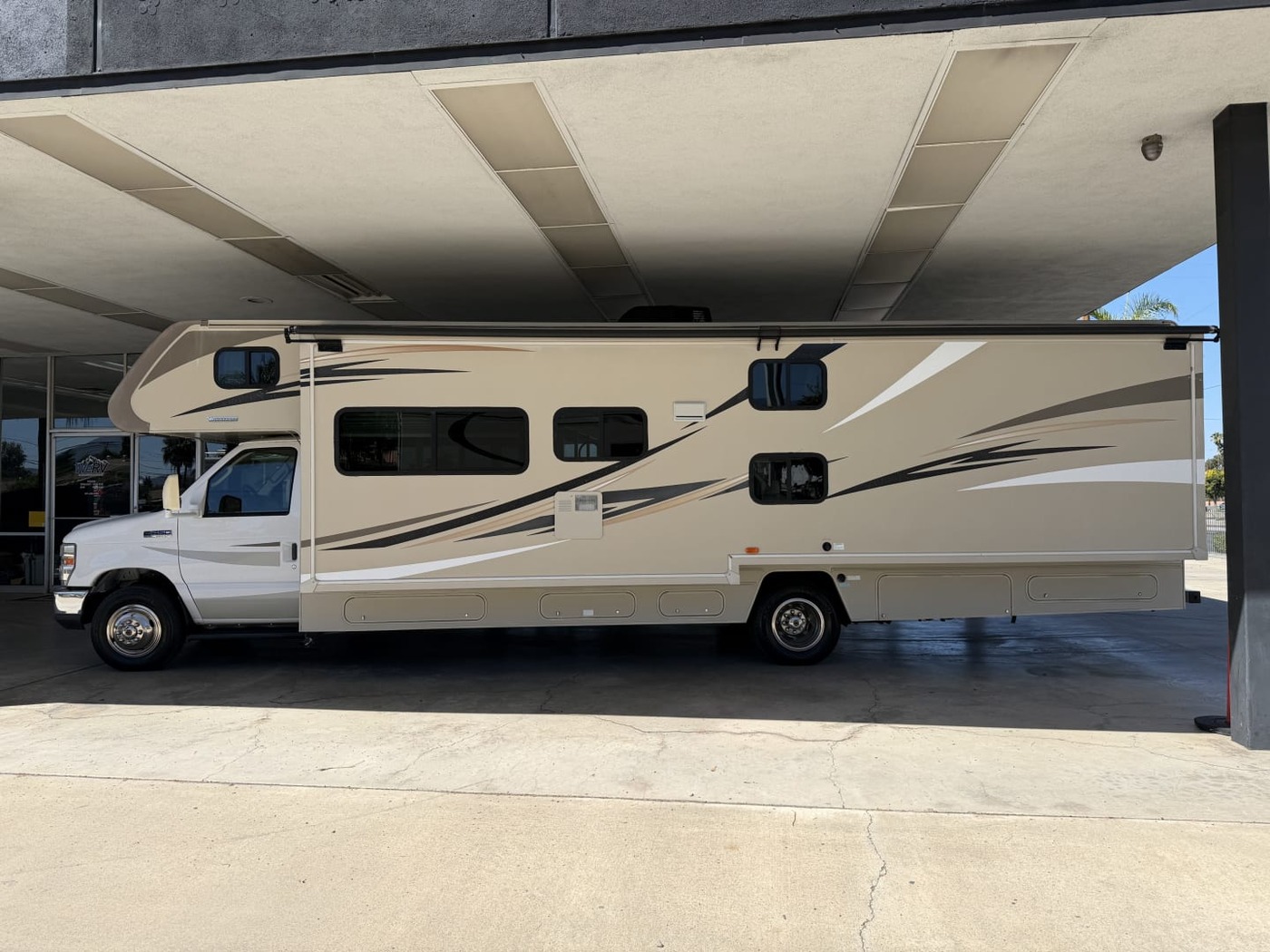 Full side profile of a Winnebago Class C motorhome under a covered lot