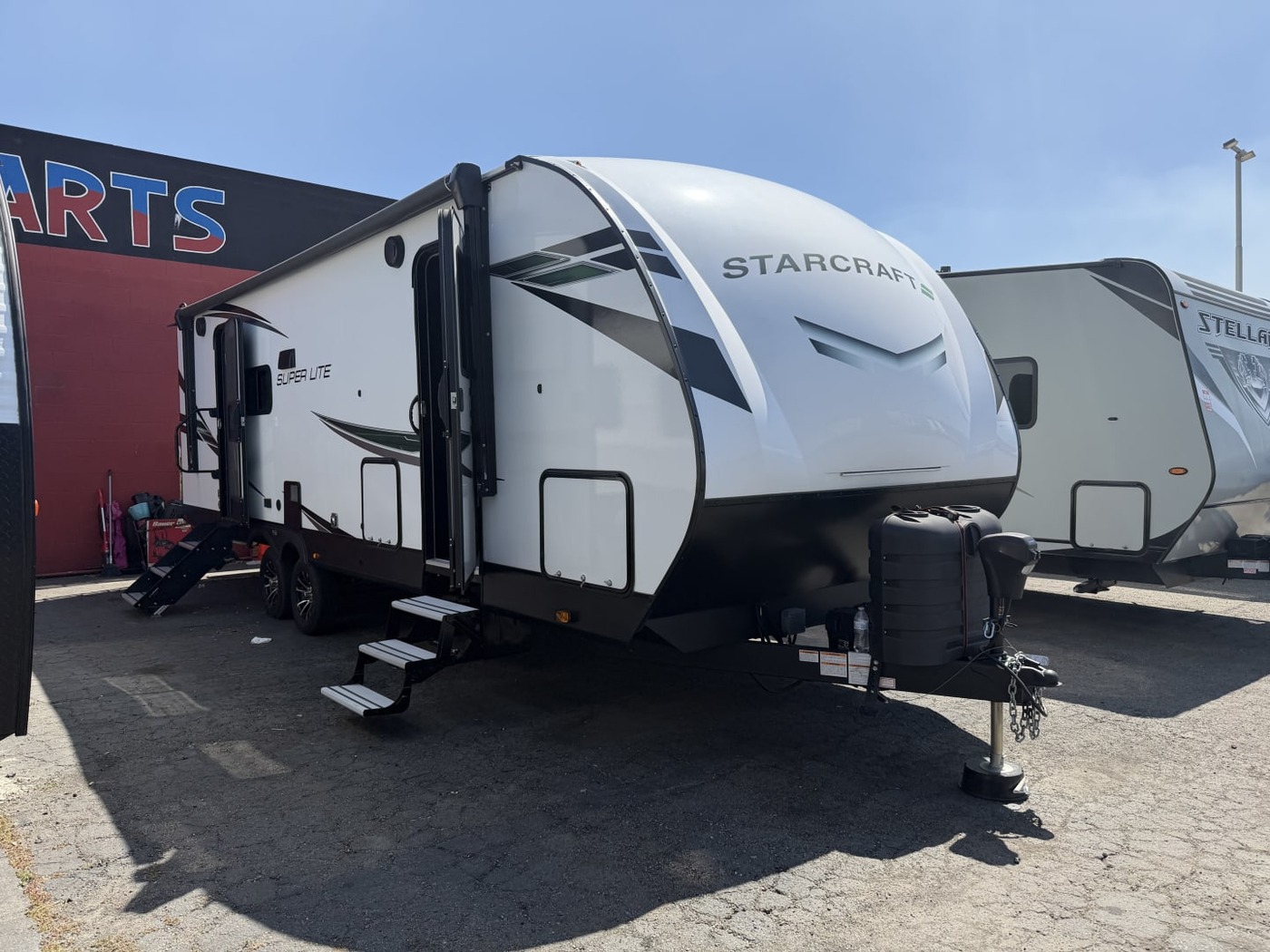 White Starcraft Super Lite travel trailer on a lot with its entry steps down and tongue jack lowered