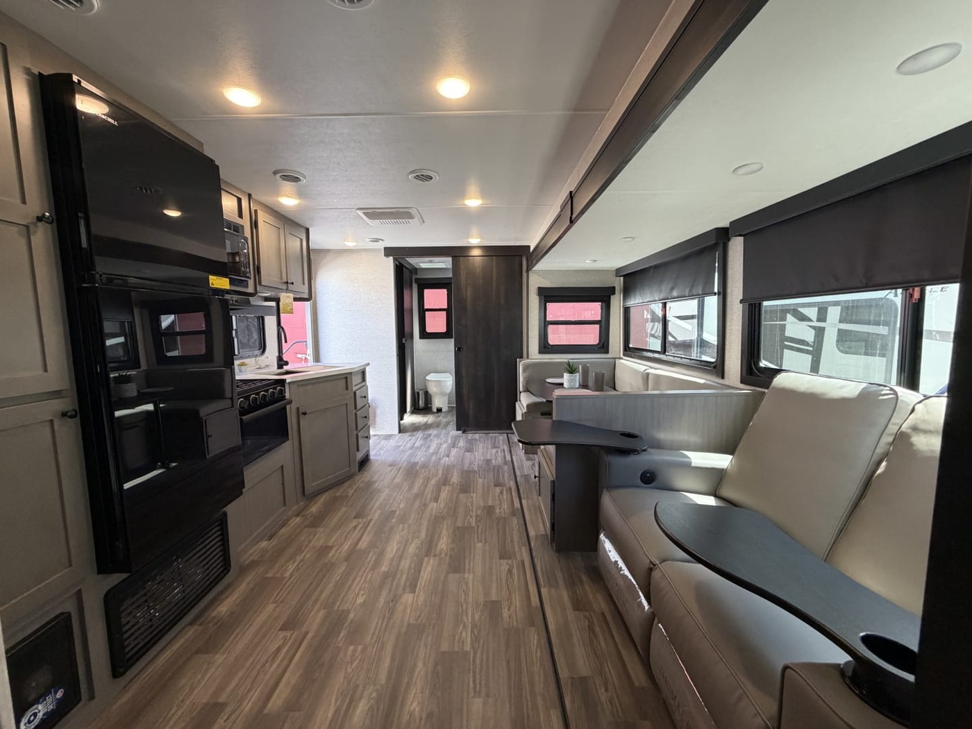 Inside a travel trailer looking down its length past the kitchen, sofa and slide-out