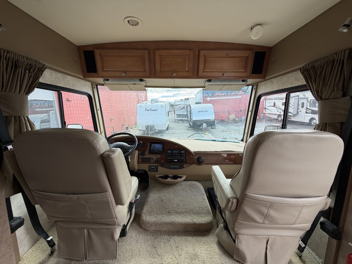 Driver and passenger seats and dashboard of a Class A motorhome seen from the living area