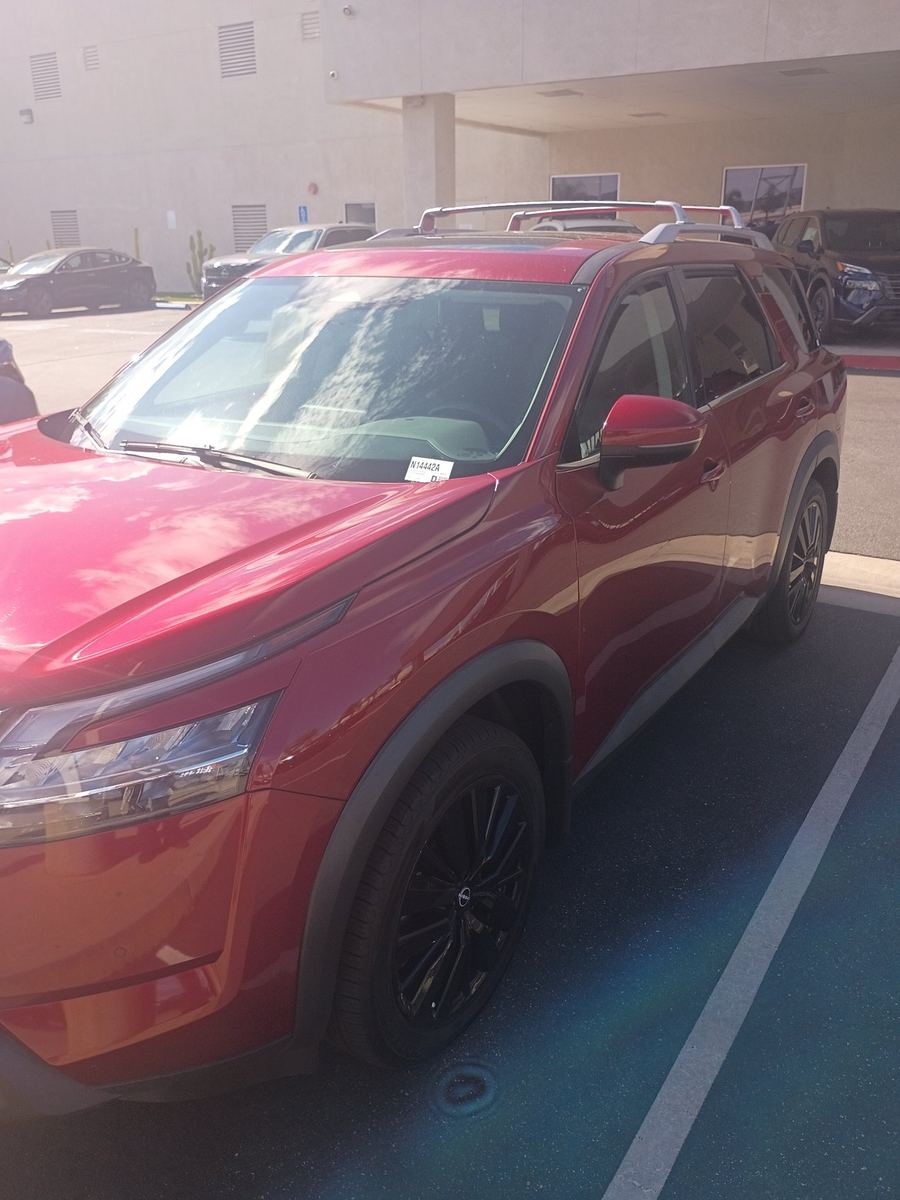 Red Nissan Pathfinder SUV parked on a dealer lot, seen from the front corner