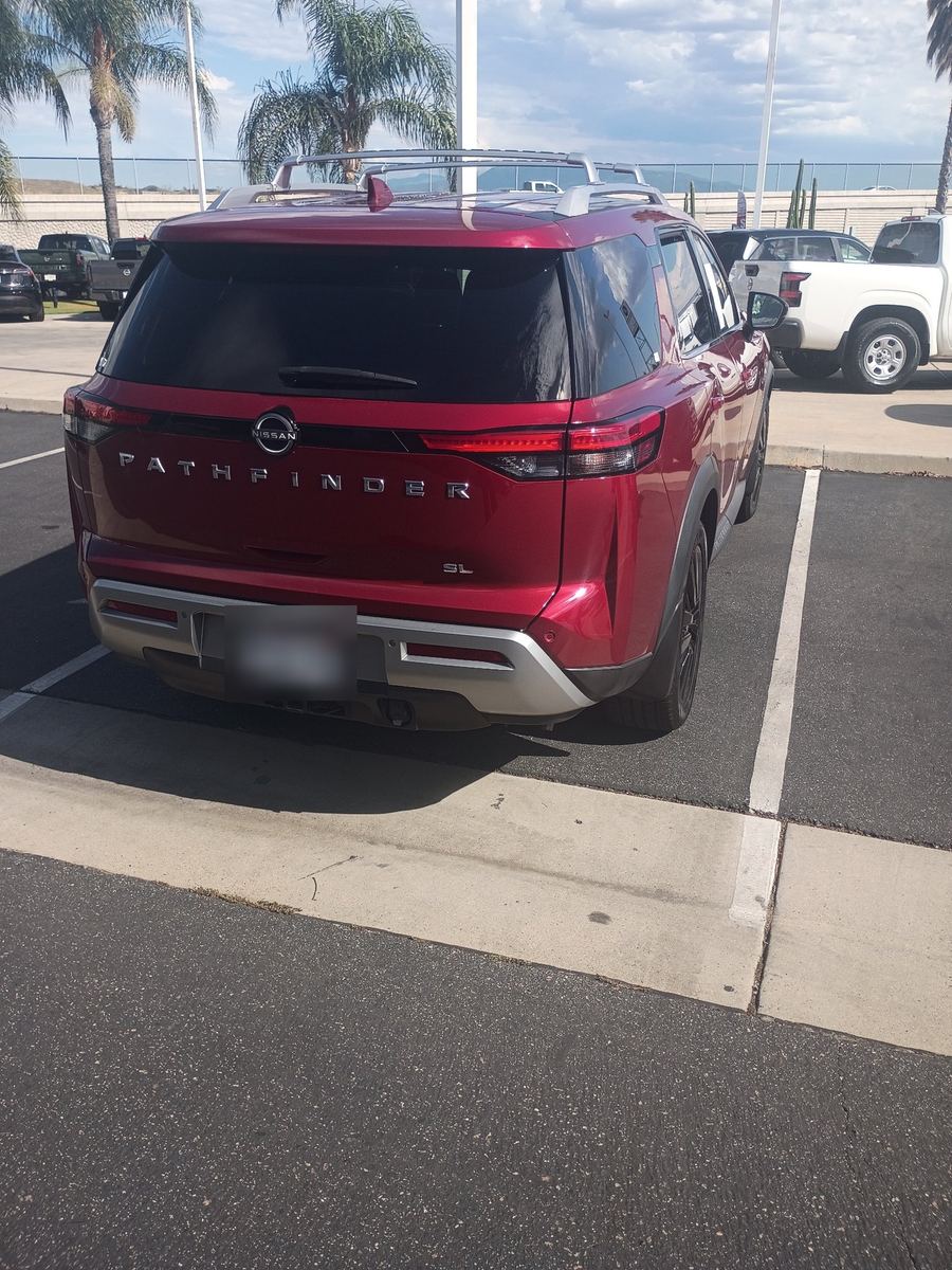 Rear of a red Nissan Pathfinder SL on a dealer lot, plate blurred out