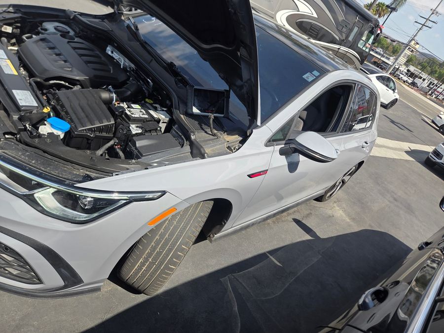 Silver Volkswagen hatchback on a dealer lot with the hood open