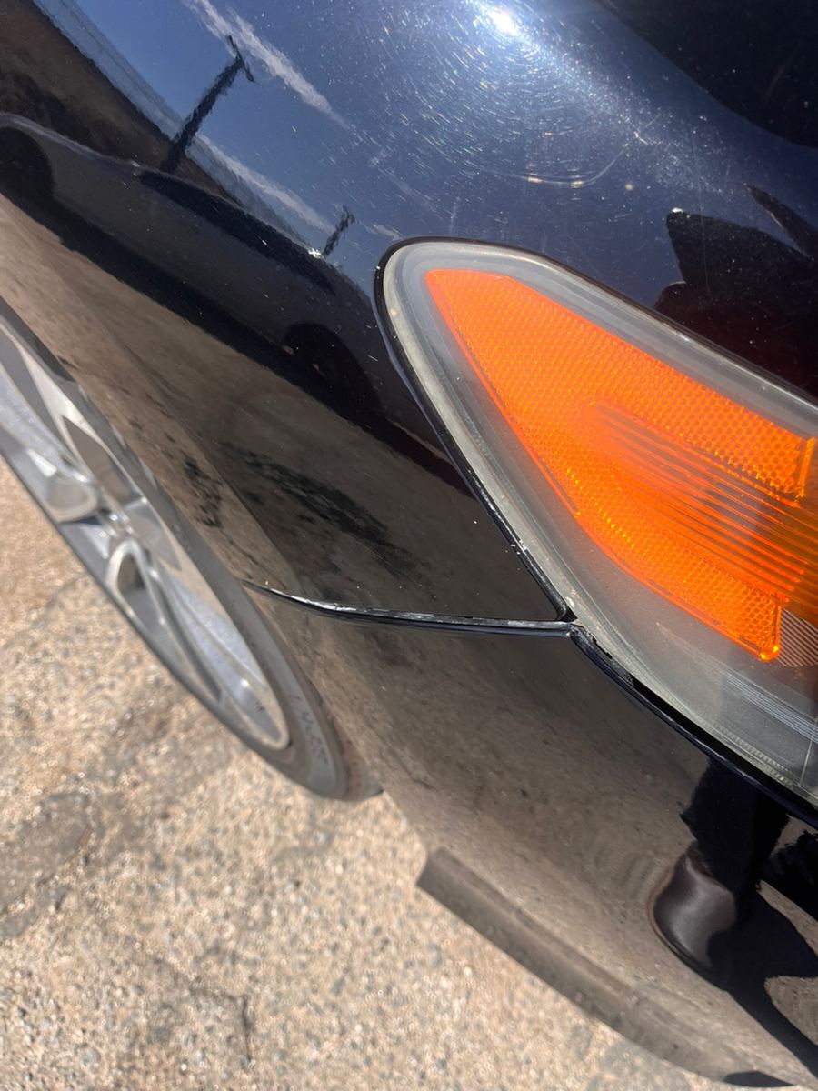 Scuffed front bumper corner and amber marker light on a black car