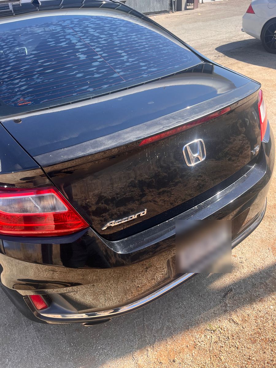 Rear of a black Honda Accord coupe, plate blurred out