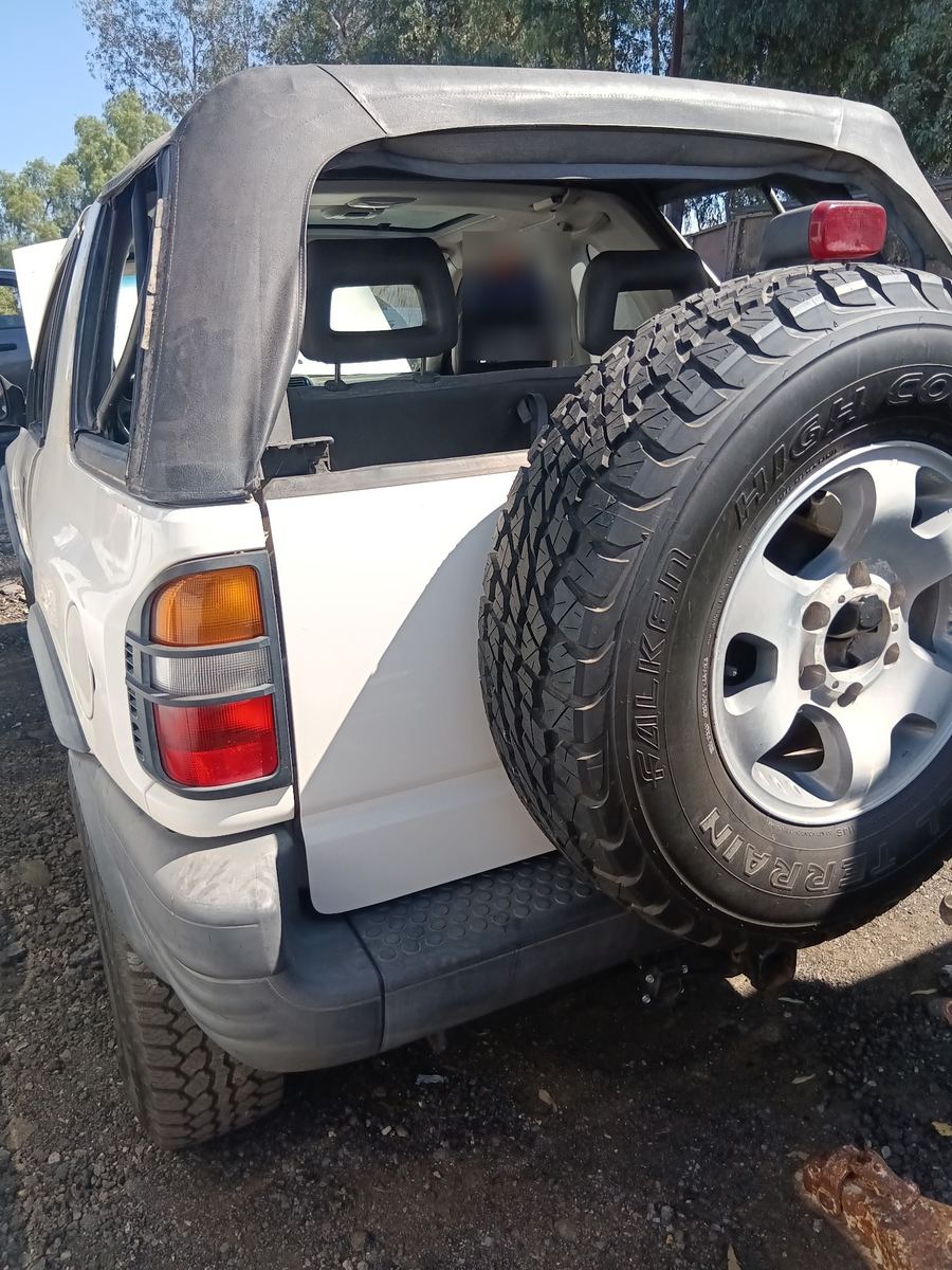 White Isuzu Rodeo with a soft top and a rear mounted spare tire