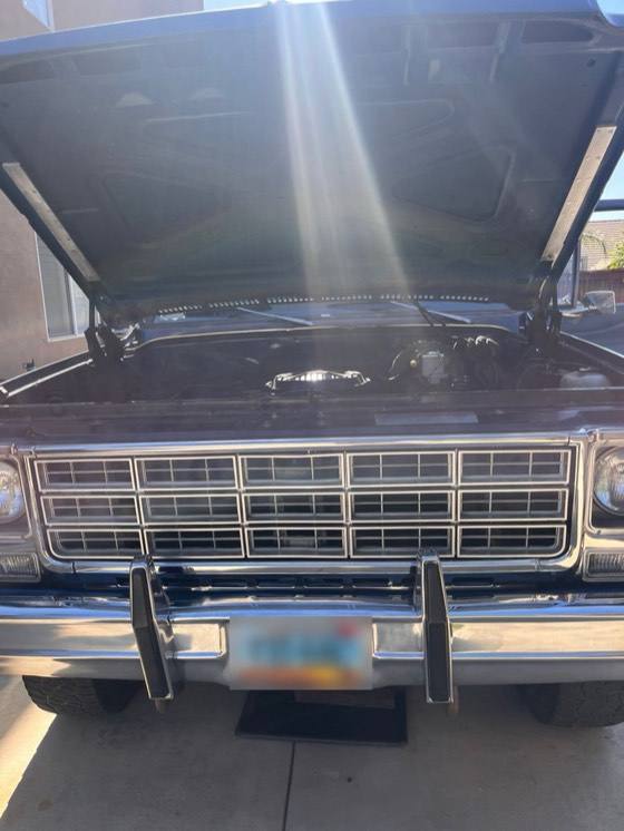 Front grille and chrome bumper of a 1979 Chevrolet K10 pickup with the hood raised